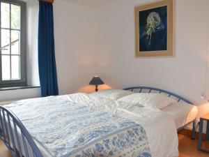 a bedroom with a bed with a blue and white blanket at Vintage Farmhouse with Garden Roofed Terrace BBQ in Gouvy