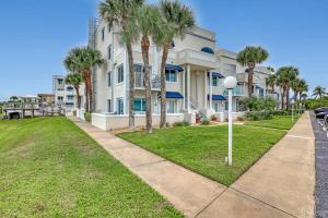 a large white building with palm trees and a sidewalk at Comfort by the Beach - Heated Pool & Private Beach in Cape Canaveral