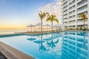 a pool with chairs and umbrellas in front of a building at Harbor NT507 by Moikkarentals in Puerto Vallarta