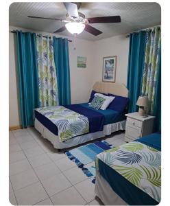 Un dormitorio con dos camas y un ventilador de techo. en So-neez Top floor apt, en Christ Church