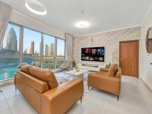 a living room with two couches and a tv at Panoramic Burj 5br Condo with Full Led & Fountain View in Dubai