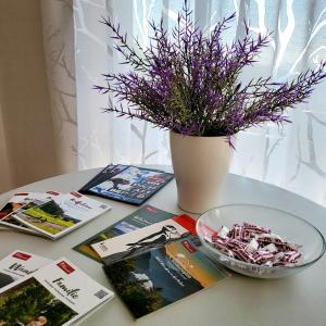 Una mesa con libros y un jarrón con flores moradas. en Mountain-top with balcony, en Schonach