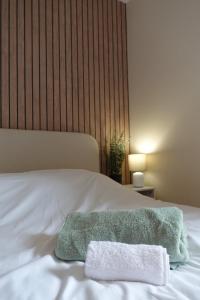 a white bed with a green towel on it at Basingstoke Train Station Short Stay in Basingstoke