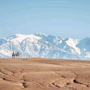 two people riding horses in the desert with mountains in the background at Agafay désert excursions tours in El Karia