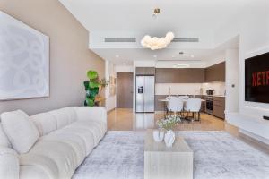a living room with a white couch and a kitchen at 2Bed with spectacular Burj Khalifa & fountain view in Dubai