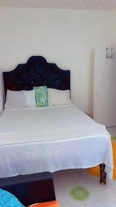 a bedroom with a large white bed with a black headboard at Tamaras Inn in Ocho Rios