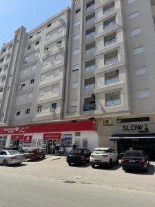 a large building with cars parked in a parking lot at Jawharet karam in El Aouina Station