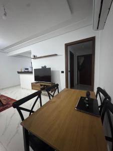 a dining room with a wooden table and a television at Jawharet karam in El Aouina Station
