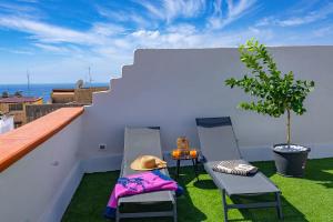 a balcony with two chairs and a table and a tree at Paradise Luxury Rooms & Spa in Sciacca