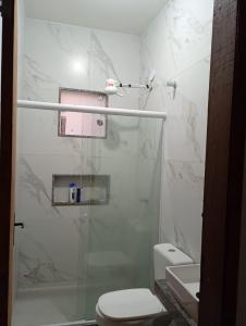 Un baño blanco con ducha y WC. en Casa da Nataliana, en Cabo Frío