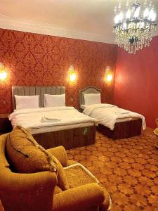 a bedroom with two beds and a chair and a chandelier at Hôtel Jeanne d'Arc Central in Baku