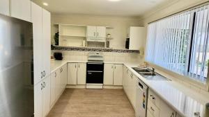 Una cocina con gabinetes blancos y un fregadero y una ventana. en Bonny View Paradise, en Bonny Hills 7 fotos más