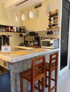 a kitchen with two chairs at a counter with a microwave at Estudio Sisal in Valladolid