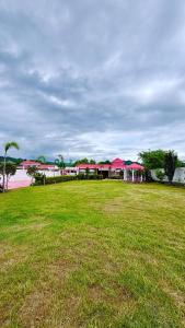 a large grass field with a building with pink roofs at Pearl Signature Farm House in Islamabad