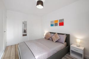 a white bedroom with a bed with two pillows at Stylish 1 Bed Apt 4 Min to Airport WiFi & Parking in Luton