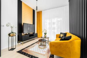 a living room with a yellow couch and a tv at Nad Odra Gold Apartment in Szczecin