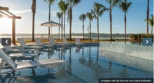 ein Swimmingpool mit Liegestühlen und Palmen in der Unterkunft Condominio Brisas do Lago in Brasilia
