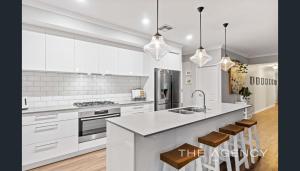 a white kitchen with a sink and a counter at Luxury Hamptons Beach House in Kinross