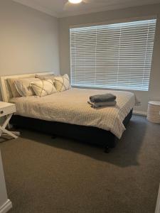 a bedroom with a large bed with a window at Luxury Hamptons Beach House in Kinross