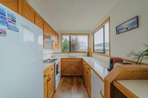 a kitchen with wooden cabinets and a sink and windows at Manawaroto 4BR with Mountain & Lake Views in Lake Tekapo