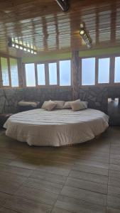 a bedroom with a large bed in a room with windows at Rancho los Alebrijes Zacatlan in Zacatlán