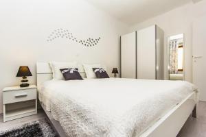a white bedroom with a large white bed and a mirror at Center Apartment Lori in Pula