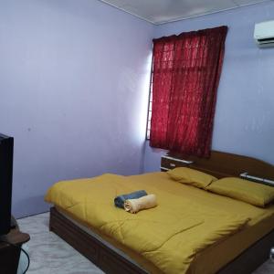 a bedroom with a bed with yellow sheets and a red window at Mastermind Malay Semeling Homestay in Bedung
