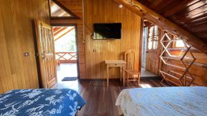 a bedroom with a bed and a television in a cabin at CABAÑAS RANCH OXaPAMP4 in Oxapampa