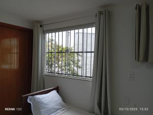 ein Fenster in einem Zimmer mit einem Bett und einem Kissen in der Unterkunft aeroporto e praia loft aconchegante in Vitória