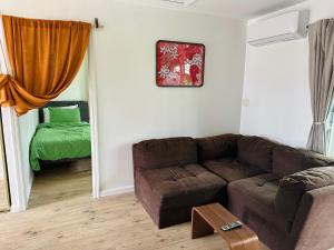 a living room with a brown couch and a green bed at Happy Hill Inn in Kailua-Kona