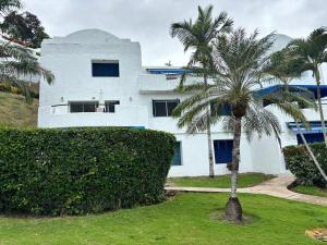 サメにあるDepartamento en Club Casa Blanca, Same, Ecuadorのヤシの木が目の前に広がる白い家