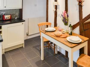 eine Küche mit einem Holztisch mit Tellern und Weingläsern in der Unterkunft Lavenham Red Brick Cottage in Lavenham