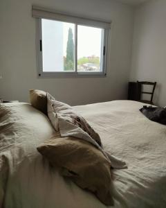 un letto con cuscini in una stanza con una finestra di Tu departamento en Olavarría te espera! a Olavarría