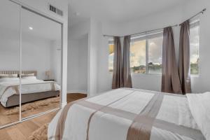 Un dormitorio blanco con una cama y una ventana grande. en Bel Air villa with canyon views and ocean glimpse, en Beverly Glen