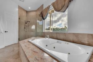 Una gran bañera blanca en un baño con ventana. en Bel Air villa with canyon views and ocean glimpse, en Beverly Glen 22 fotos más