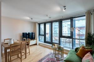 a living room with a table and a couch and a room withwindows at Luxury 2-Bed Penthouse In Deansgate I Free Parking in Manchester