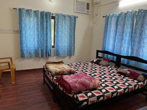 a bedroom with a bed and blue curtains at Adichunchangiri Mahasamsthana Math in Naimishāranya
