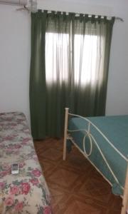 a bedroom with a bed and a green curtain at El Sosiego in Trelew