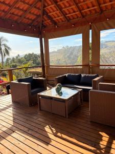 a porch with a couch and a table on a deck at Santuário Panacéia in Piracaia +15 photos