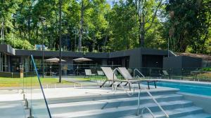 a building with a swimming pool and chairs next to a building at Pucon Infinity Camino al Volcán in Pucón