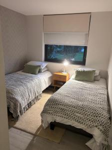 two beds in a small room with a window at Pucon Infinity Camino al Volcán in Pucón +11 photos