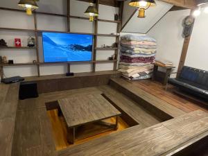 a living room with a flat screen tv and a table at Karamatsu Lodge in Hakuba