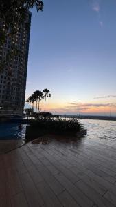 a sunset over the water with palm trees and a building at Apartemen Anderson 28 1 Pakuwon mall Luxury Studio Apartment Connecting Mall, Pool & City View in Surabaya