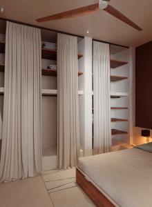 a bedroom with white curtains and a bed and a tv at Gate 11 Apartments in Denpasar