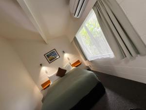 a bedroom with a green bed and a window at Kerikeri Court Motel in Kerikeri