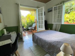 a bedroom with a bed and a door to a patio at Chambres d'hôtes créoles aux Avirons, idéal rando - FR-1-786-68 in Ravine Sèche +14 photos