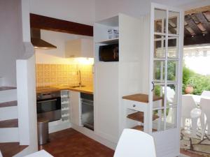 une cuisine avec des armoires blanches et une table et des chaises dans l'établissement Charmant mas 4 personnes avec piscine et parking à La Croix-Valmer - FR-1-726-60, à La Croix-Valmer