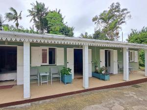 a green house with chairs and tables on a porch at Chambre authentique créole aux Avirons - FR-1-786-69 in Ravine Sèche