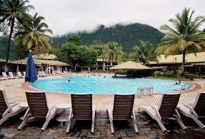 a pool with chairs and people in a resort at Damai Beach Resort in Santubong