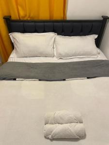 a white bed with a black headboard and white pillows at Cozy Kipepeo Cottage in Nairobi